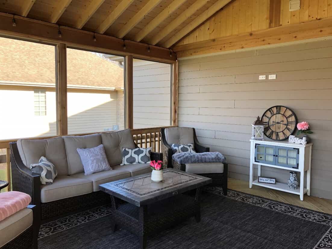 Inside of a screened porch decorated for spring with pink flowers.